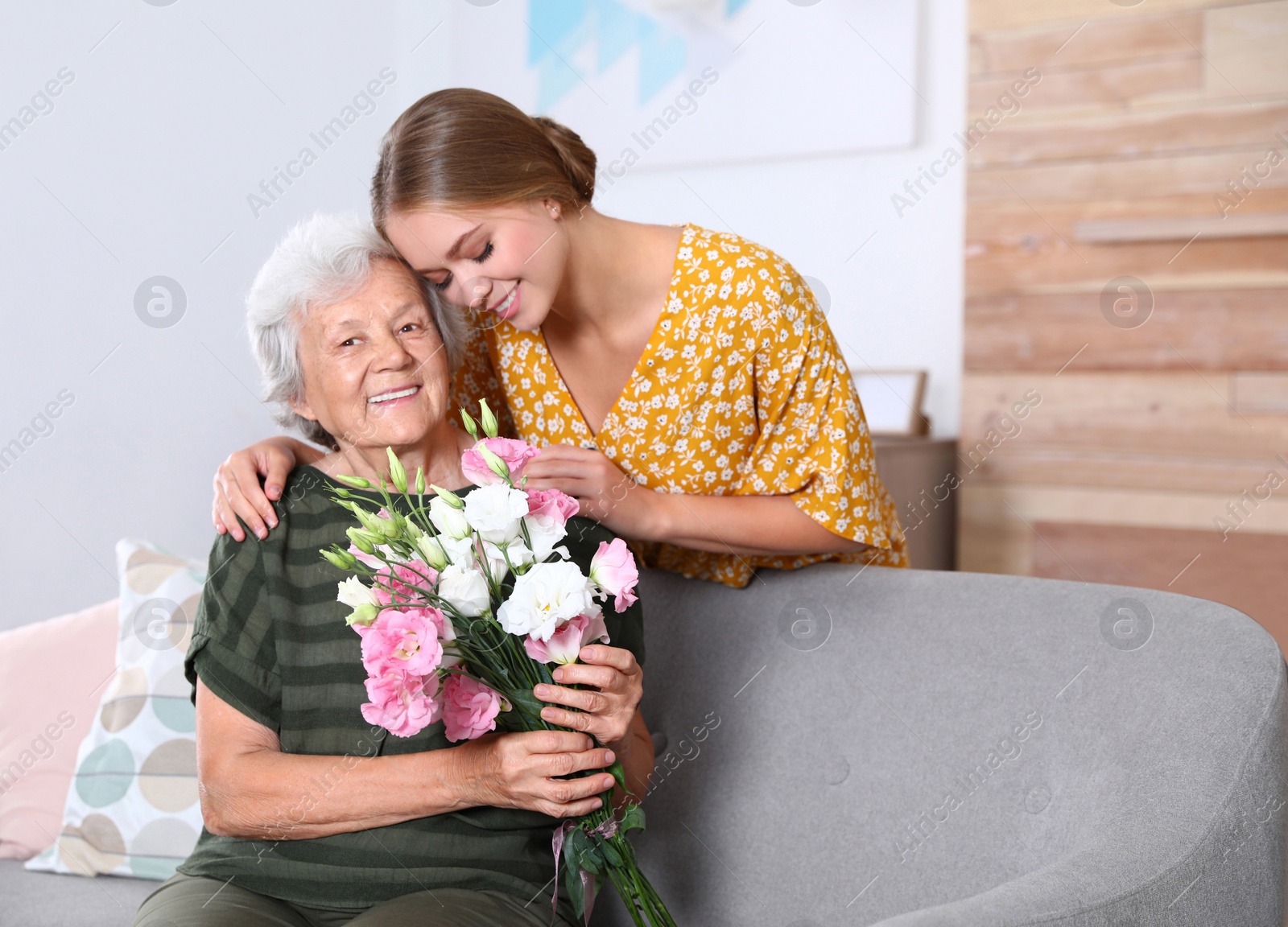 Photo of Young woman congratulating her senior mom at home. Happy Mother's Day