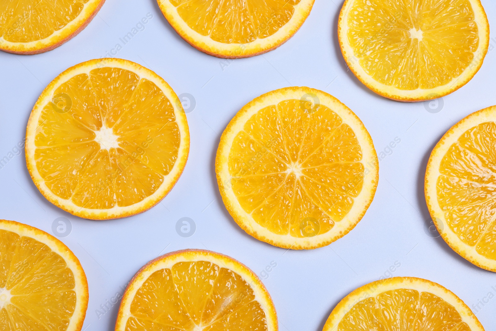 Photo of Slices of juicy orange on light blue background, flat lay