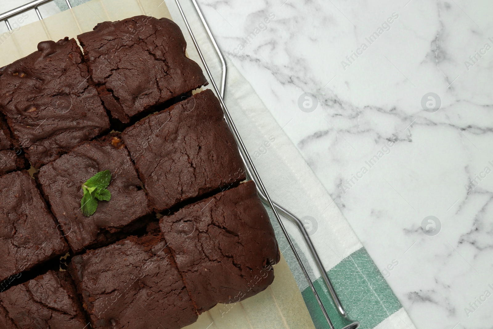 Photo of Delicious freshly baked brownies on white marble table, top view. Space for text