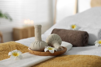 Photo of Herbal bags, flowers and towels on massage table in spa