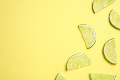 Photo of Juicy fresh lime slices on yellow background, flat lay. Space for text