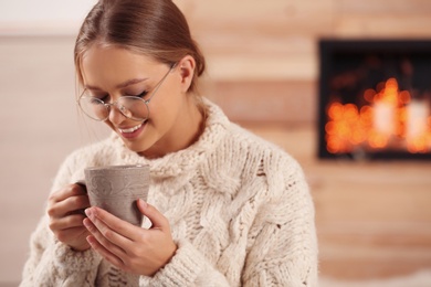 Beautiful young woman with cup of hot drink at home. Winter atmosphere