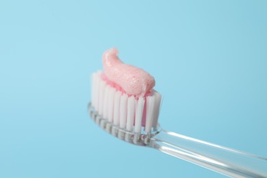 Photo of Brush with toothpaste against turquoise background, closeup