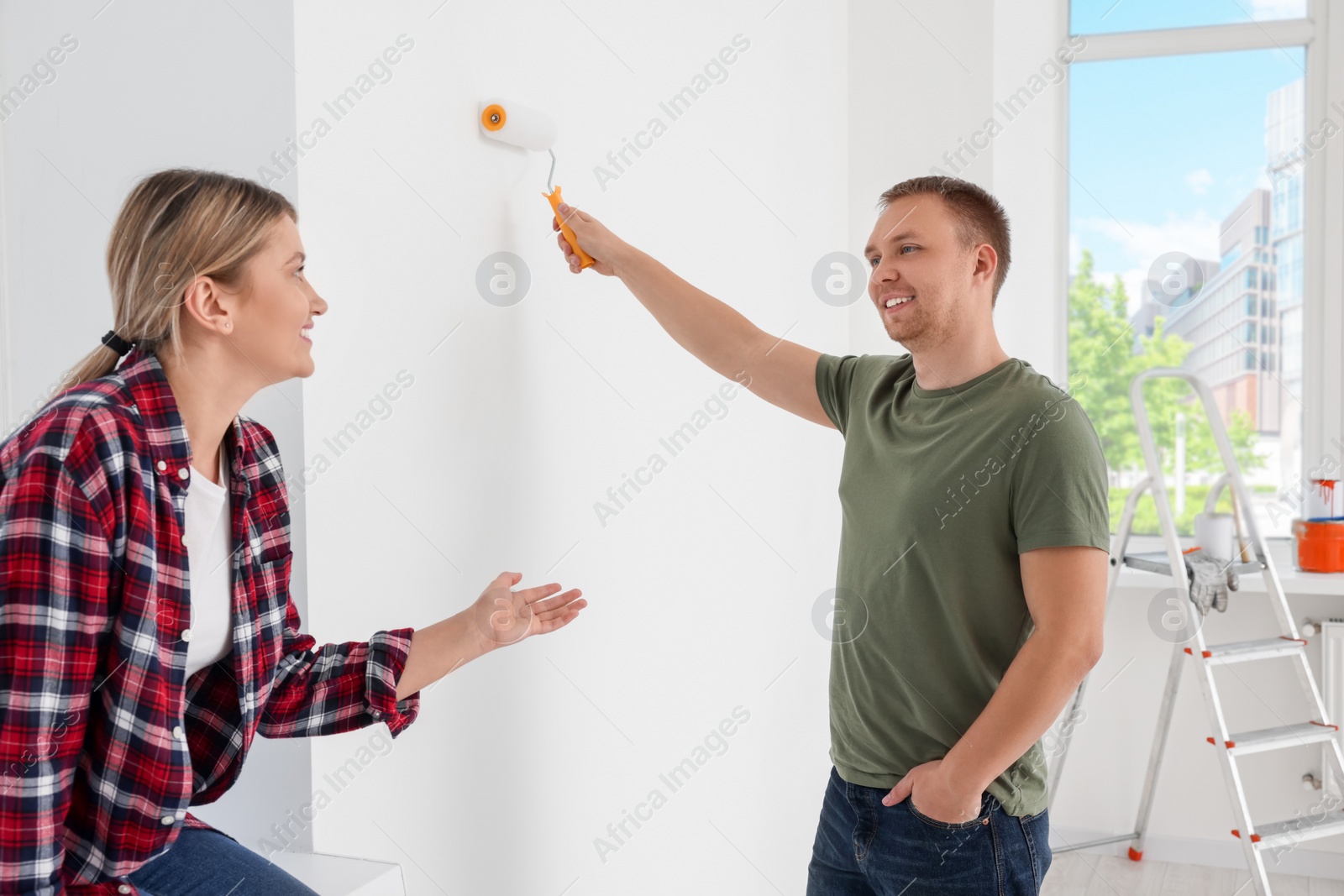 Photo of Happy couple discussing interior details in apartment during repair