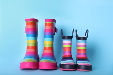 Photo of Two pairs of striped rubber boots on light blue background