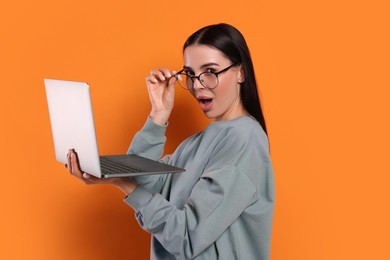 Photo of Surprised woman with laptop on orange background