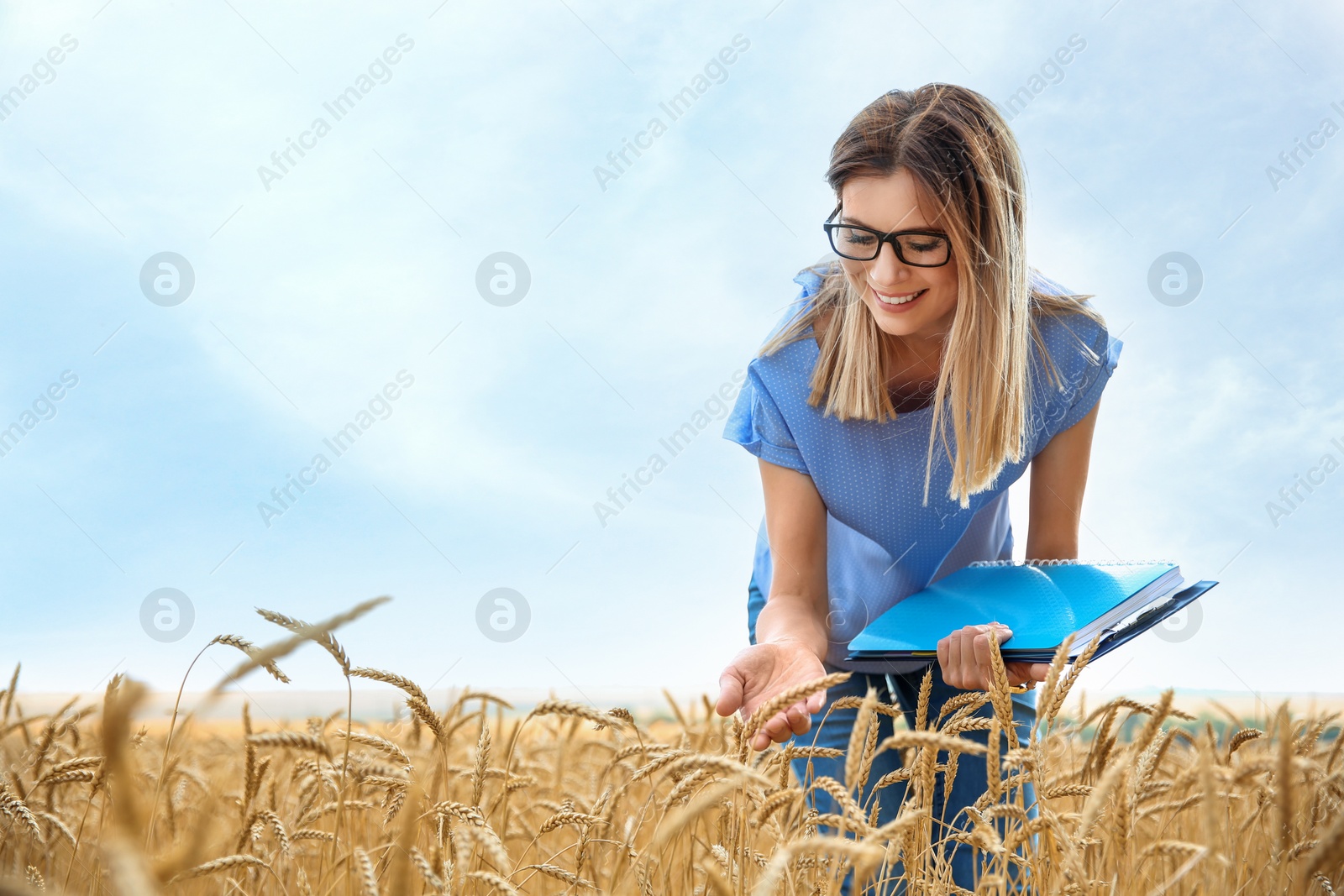 Photo of Young agronomist with clipboard and notebook in grain field. Cereal farming