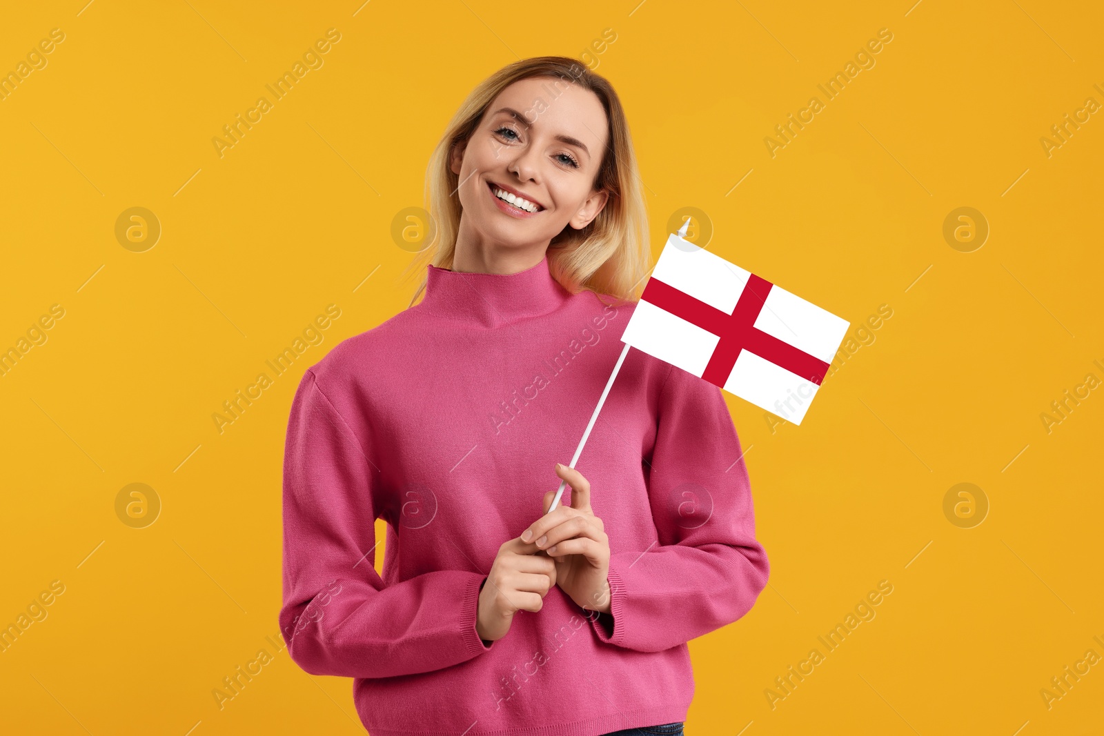 Image of Happy young woman with flag of England on yellow background