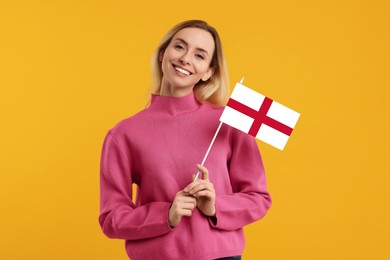 Happy young woman with flag of England on yellow background