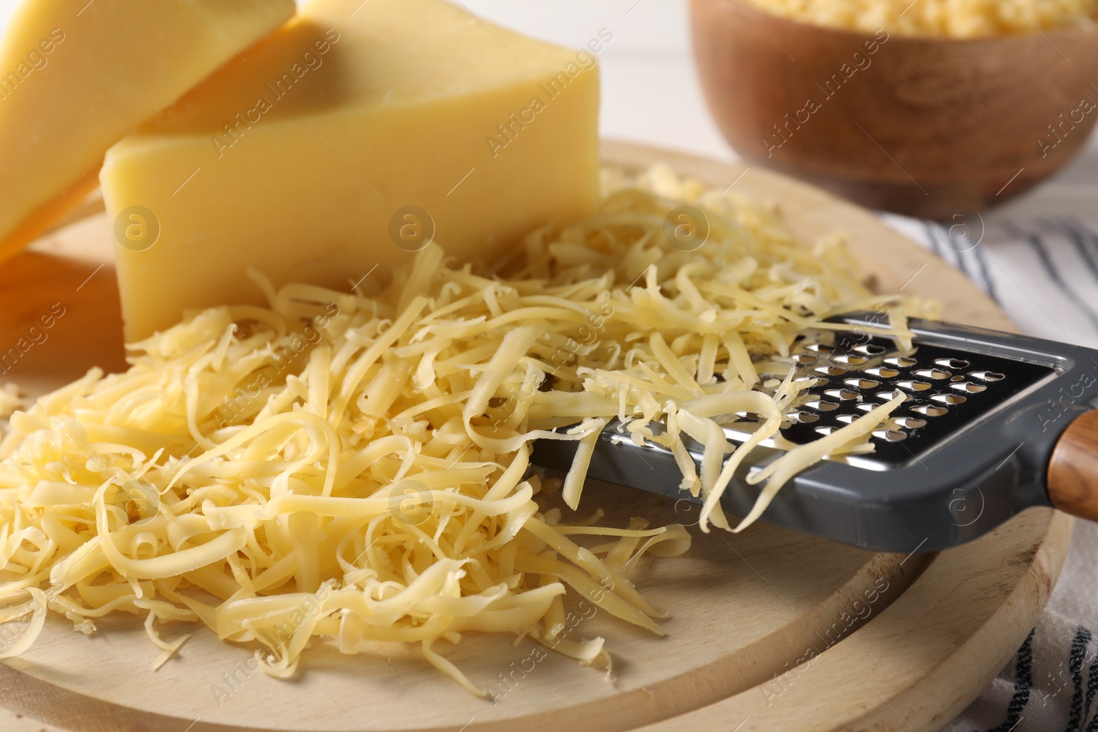 Photo of Grated, whole pieces of cheese and grater on board, closeup