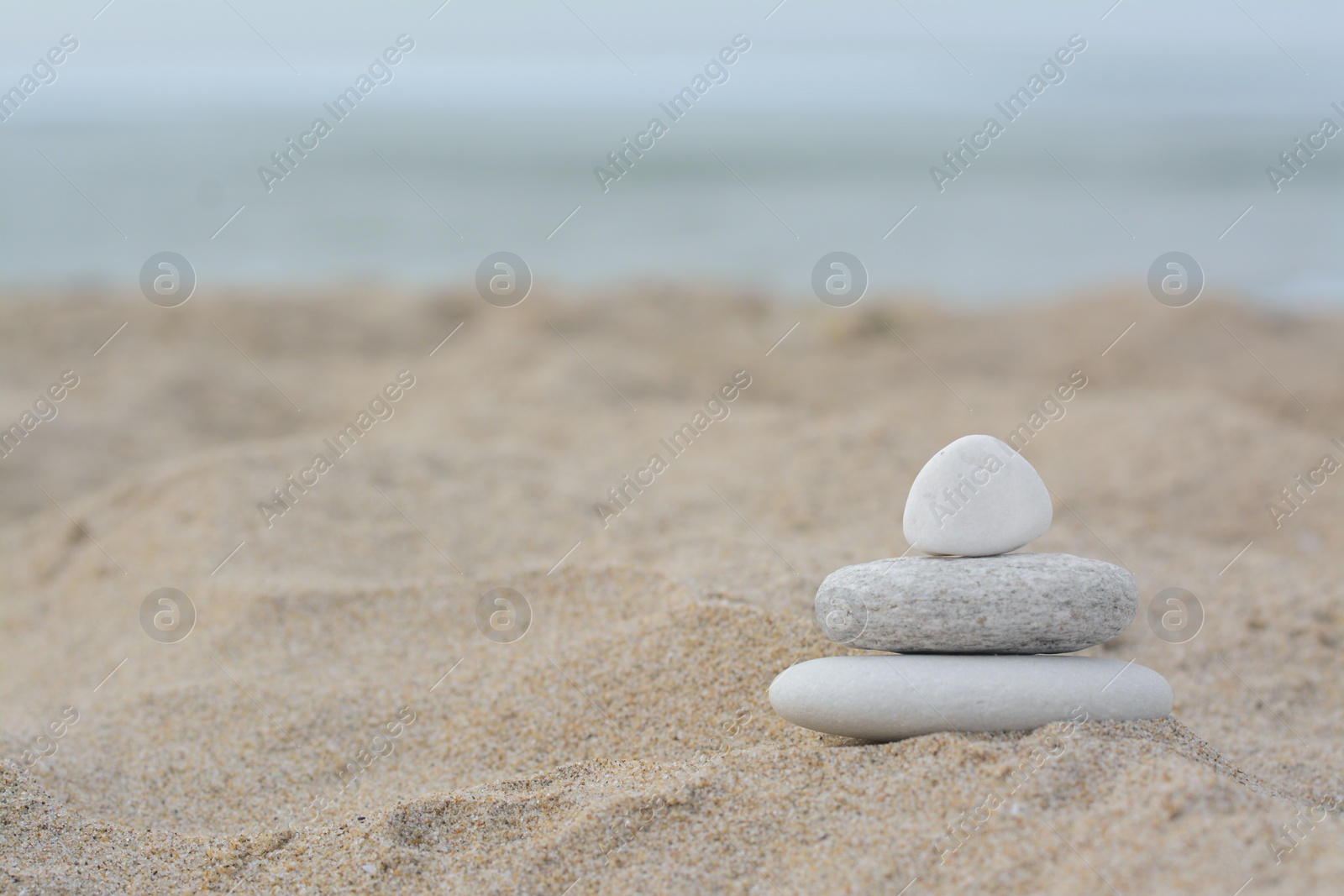 Photo of Stack of stones on sandy beach near sea, space for text
