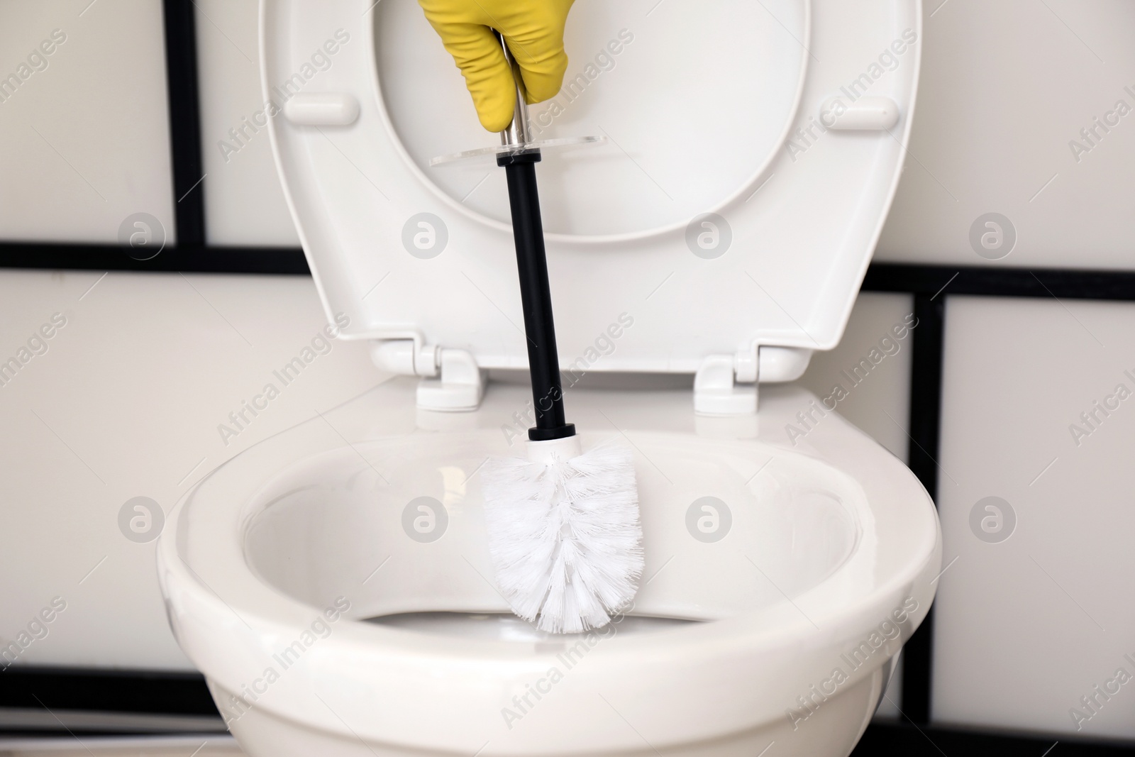 Photo of Man cleaning toilet bowl in bathroom, closeup