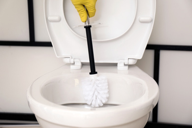 Man cleaning toilet bowl in bathroom, closeup