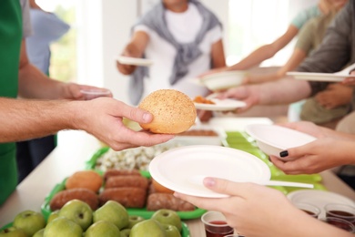 Volunteers serving food for poor people indoors