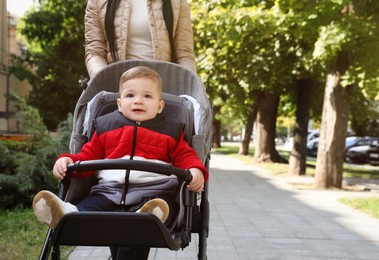 Photo of Mother walking with her son in stroller outdoors