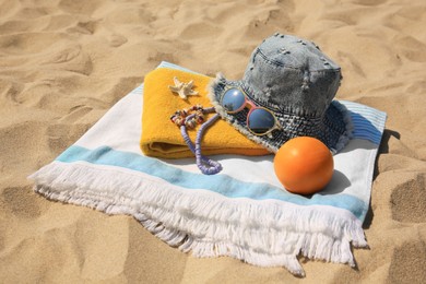 Photo of Denim hat, orange and beach accessories on sand