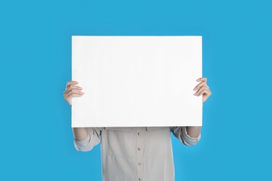 Photo of Woman holding blank poster on blue background