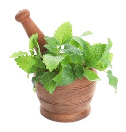 Photo of Wooden mortar with pestle and fresh green lemon balm leaves isolated on white