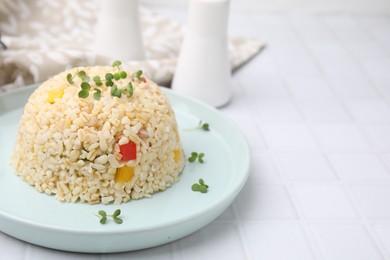 Photo of Delicious bulgur with vegetables and microgreens on white table, closeup. Space for text