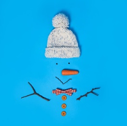 Photo of Creative snowman shape made of different items on light blue background, flat lay