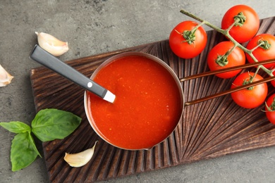 Photo of Flat lay composition with pan of sauce and tomatoes on grey table