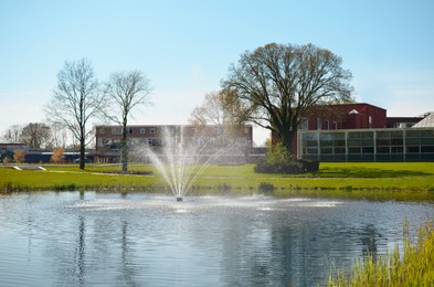 Photo of Beautiful pond with fountain under blue sky. Picturesque landscape