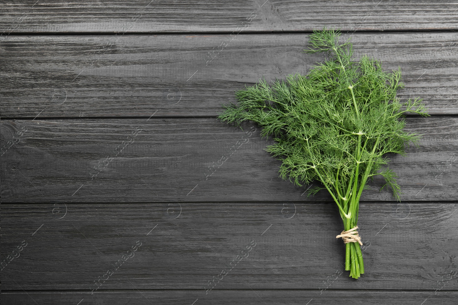 Photo of Bunch of fresh green dill on grey wooden table, top view. Space for text