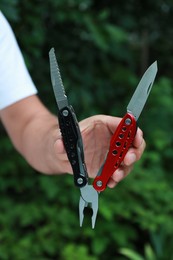 Photo of Man holding compact portable multitool outdoors, closeup