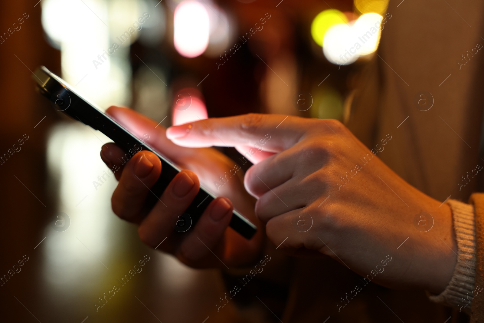 Photo of Woman using smartphone on night city street, closeup