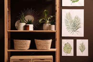 Photo of Rack with different decor and houseplants near brown wall