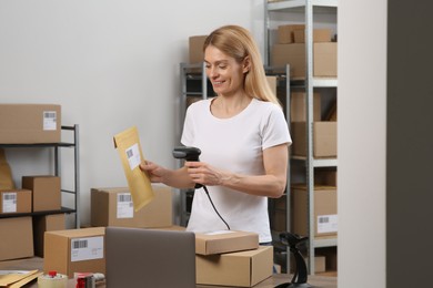 Photo of Seller with scanner reading parcel barcode at workplace. Online store