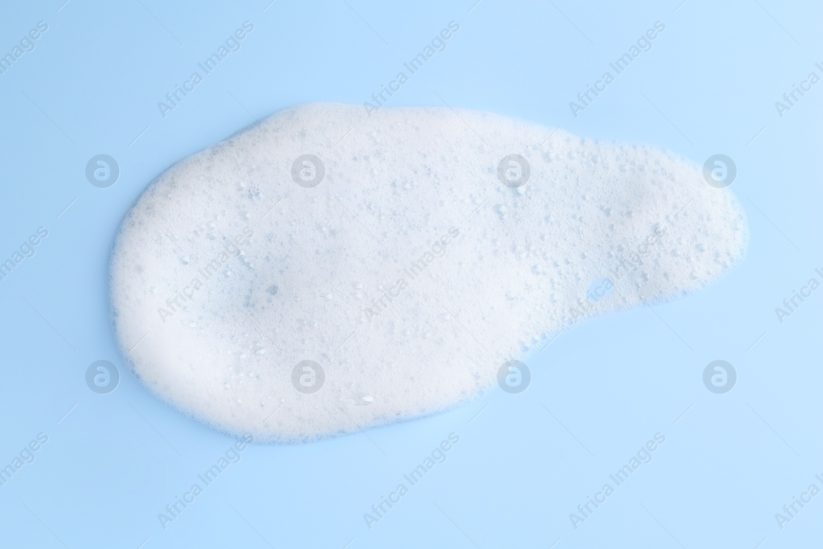 Photo of Sample of fluffy foam on light blue background, top view