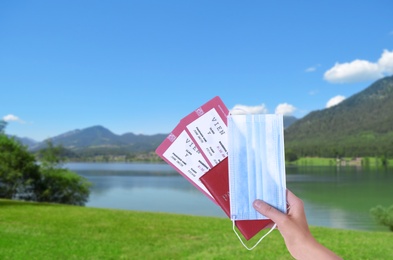 Image of Woman holding passport, tickets and protective mask outdoors, closeup. Travel during quarantine