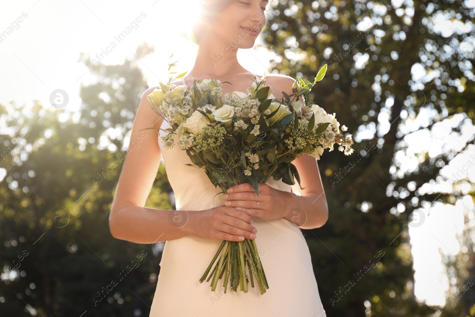 Photo of Bride in beautiful wedding dress with bouquet outdoors, closeup