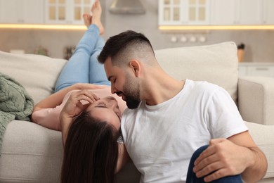 Affectionate young couple kissing on sofa indoors