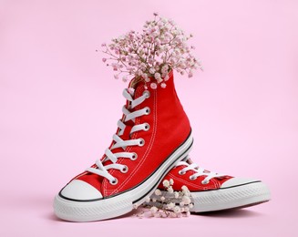 Photo of Pair of new stylish red sneakers with gypsophila flowers on pink background