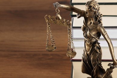 Photo of Symbol of fair treatment under law. Figure of Lady Justice and books on wooden table, closeup with space for text