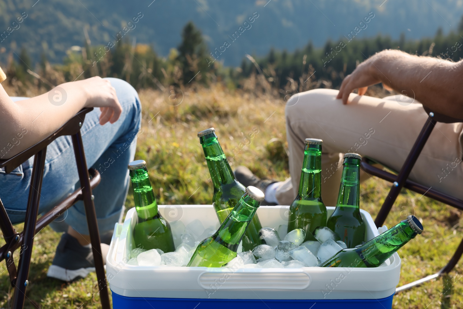 Photo of Couple and cool box with bottles of beer in nature, closeup