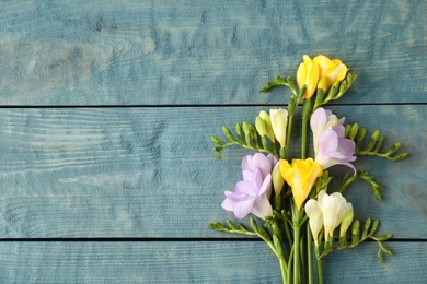 Photo of Beautiful fresh freesia flowers on wooden background, top view. Space for text