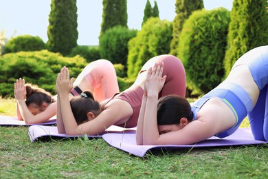 Photo of Young women practicing yoga on mats outdoors