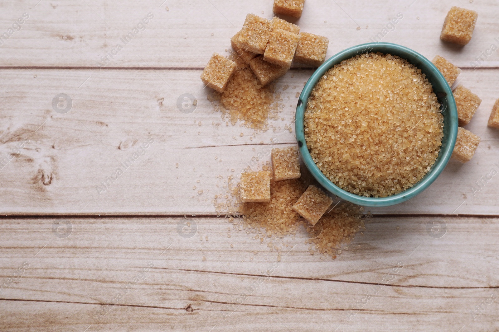 Photo of Refined and granulated brown sugar on white wooden table, flat lay. Space for text