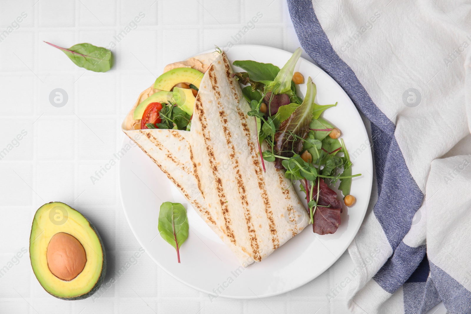 Photo of Plate with hummus wrap and vegetables on white table, flat lay