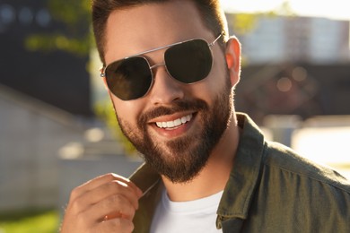 Handsome smiling man in sunglasses outdoors on sunny day