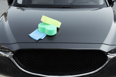 Sponges and rag on car hood outdoors. Cleaning products