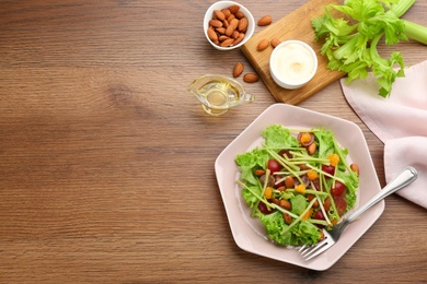 Photo of Delicious fresh celery salad served on wooden table, flat lay. Space for text