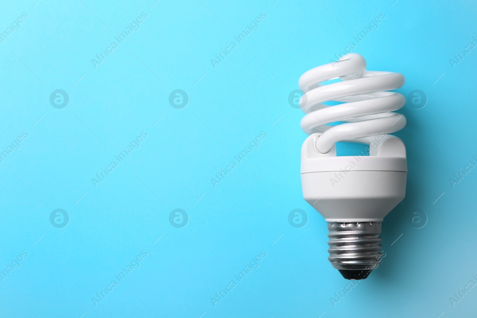 Photo of New modern lamp bulb on light blue background, top view. Space for text