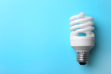 Photo of New modern lamp bulb on light blue background, top view. Space for text