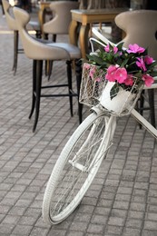 Photo of Retro bicycle with flowers in basket on outdoor terrace