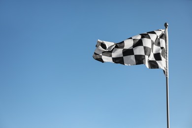 Photo of Checkered finish flag on light blue background. Space for text