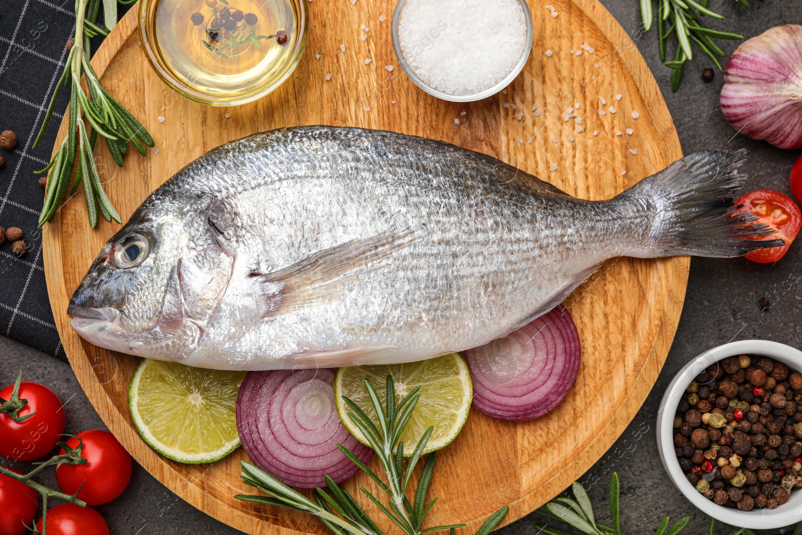 Photo of Fresh dorado fish and ingredients on black table, flat lay